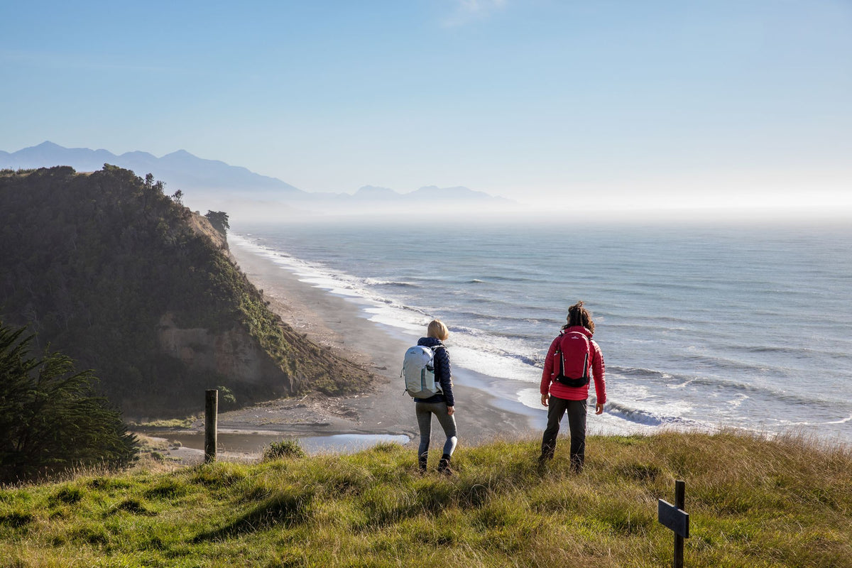 Two people hiking wearing Kathmandu Puffer Jackets and hiking bags