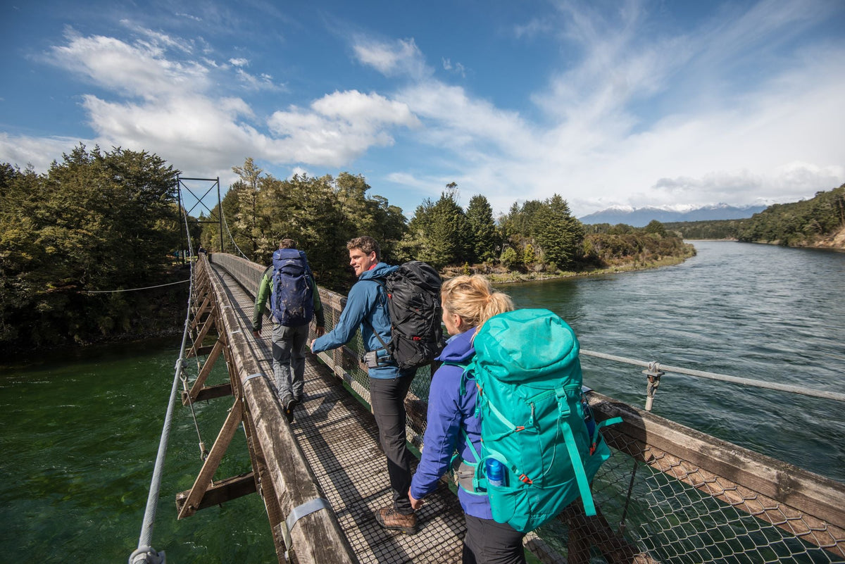 A group of hikers with their packs is crossing a bridge on a multi day hike.